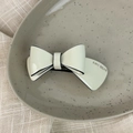 Detailed close-up of cream acetate double-layered bow hair clip on a textured fabric - 3D Bow-Off White