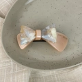 Detail of acetate double-layer bow hair clip with marbled texture and AMY BEAR engraving - 3D Bow-Light Orange
