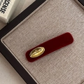Detail van rode fluwelen haarclip met gouden handmade plaatje en retro textuur - Bordeauxrood