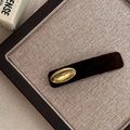 Detailopname van een fluwelen haarspeld met gouden plaatje op een linnen achtergrond - Bruin