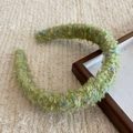 Detail of green fuzzy wool headband with colorful textured yarn accents on fabric background - Fruit Green