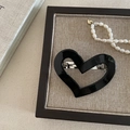 Close-up of black hollow heart acetate hair clip with silver metal spring fastener - Black