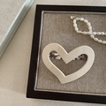 Detail of cream acetate heart hair clip with silver metal spring on wooden base - Off White