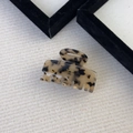 Detail of tortoise shell hair claw clip with gold France lettering on knit background - Light Tortoiseshell