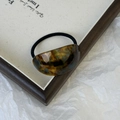 Detail showing the tortoiseshell pattern resin arc on a minimalist black hair tie - Blue Brown Gradient