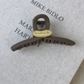 Pinza per capelli caffè opaco con dettaglio in metallo dorato handmade su sfondo di stoffa - Marrone