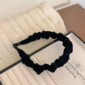 Close-up of a black velvet pleated headband resting on a creamy white velvet jewelry box - Black Velvet Headband