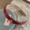 Dettaglio macro del cerchietto in pelle PU rosso vino con un ciondolo floreale in oro - Stile Fiore