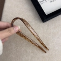 Detail view of acetate U-shaped hair pin with leopard print pattern and gold text - Tortoiseshell