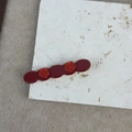Detailed close-up of dark wine red acetate rose hair clip on natural stone texture - Red