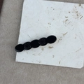Close-up of black acetate rose clip with glossy floral carvings on a marble stone surface - Black