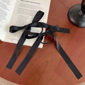 Detalle de un elegante coletero con lazo de satén negro colocado sobre un libro abierto - Wide Satin Style