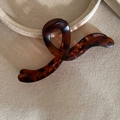Macro shot of large dark tortoiseshell hair claw clip with S-shaped curve on canvas - Tortoiseshell Curve