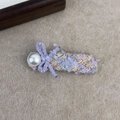Close-up of pink tweed hair clip with purple knit bow and large white pearl detail - Square Style / Purple Bow Square Style