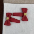 Vue détaillée de deux barrettes à nœuds rouges en tissu avec fleurs dorées gaufrées - Paire de Clips BB