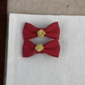 Détail de barrettes nœuds en tissu rouge ornées d'une décoration centrale de rose dorée - Paire de Pinces à Cheveux Noeud
