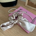 Detalle de coletero de satén champán con lazo y collar de perlas en libro rosa - Grupo de Coletero con Lazo y Collar / Blanco Roto