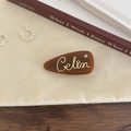 Nahaufnahme einer braunen Acetat-Haarklammer mit goldenen Buchstaben und Kristall - Braun