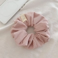 Close-up of pink corduroy scrunchie fabric texture with soft woven brand label detail - Light Pink