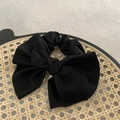 Elegant black satin bow scrunchie for women, shown on a rustic round woven tray - Black