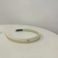 Détail d'un serre-tête en satin champagne avec logo en métal doré et étiquette fait main - Blanc Cassé