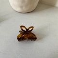 Detail view of small amber butterfly hair claw clip with hollow tortoiseshell wing design - Brown