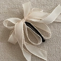 Détail d'une pince banane à nœud crème avec ruban texturé et design multicouche - Blanc Cassé