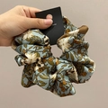 Dettaglio dell'elastico scrunchie in satin a fiori azzurro con motivo vintage - Verde Fagiolo