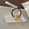 Vue à plat d'un élastique ours jaune mignon et d'une bague coeur argentée ouverte - Cravate à cheveux / Jaune
