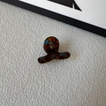 Detailopname van mini haarklem van acetaat in schildpadmotief met de tekst SUNSHINE - Blauw bruin verloop