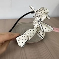 Detail of elegant black headband with large beige polka dot bow and fine black stitching - Off-white