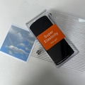 Macro shot of durable black elastic hair ties set in a transparent box with orange label - Black