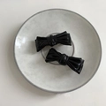 Detailansicht von zwei eleganten schwarzen Leder-Haarspangen auf einem Keramiktablett - Schwarz