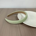 Detail of light green braided headband featuring thick texture on a wooden surface - Green Waffle Grid