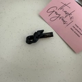Detail of a black glossy resin twist bow hair clip featuring gold France Handmade lettering - Black