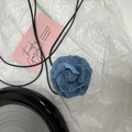 Detailansicht der handgefertigten Jeans-Kamelienblüte mit schwarzem Band auf weißem Papier - Groß / Hellblau