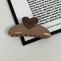 Detailed close-up of a glossy cream and chocolate heart-shaped hair claw clip with firm grip - Brown