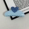 Detail view of a glossy light blue heart hair claw clip with cream finish for daily hairstyles - Blue
