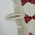 Detail of a beige oval acetate hair barrette with Barrette La France text and metal clip - Off White