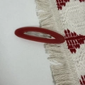 Detailed macro of a red matte oval acetate hair clip with silver metal spring component - Red