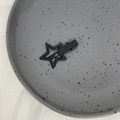 Primer plano de una pinza para el pelo con estrella negra mate en bandeja decorativa - Negro