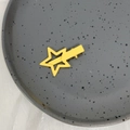 Detalle del pasador de estrella amarilla mate sobre un plato de cerámica blanca - Amarillo