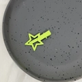 Primer plano de una pinza para el cabello de estrella verde neón mate sobre plato - Verde