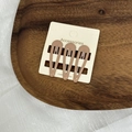 Vue détaillée de trois pinces à cheveux crème présentées sur une carte cadeau - Marron