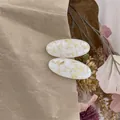 Detailed macro of oval resin hair clips featuring yellow dried flowers and a vintage aesthetic - Cream