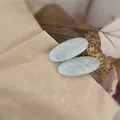 Detail of light blue oval resin hair clips with gold foil flakes on vintage background - Blue