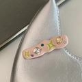 Détail macro d'une pince à cheveux Y2K en résine rose avec strass colorés et étoiles - Vague Rose Clair