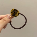 Detail shot of a resin rose hair tie with brown tortoise shell pattern held by hand - Dark Leopard Print
