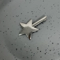 Dettaglio macro della molletta a stella in argento spazzolato con trama in metallo - Canna di Fucile