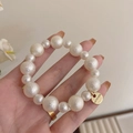 Eleganter Baumwollperlen-Haargummi mit goldenem Morava-Tag als Armband getragen - Matte Texturierte Perle Stil
